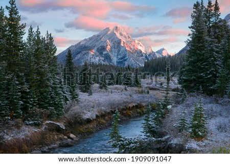 Canadian Rocky Mountain nature scene during a beautiful sunrise with a dusting of overnight snow and frost on the trees and ground. 