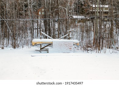 Canadian Winter Scene - A Canoe Covered In Snow Against A Backdrop Of Bare Trees, Wakefield, Quebec, Canada