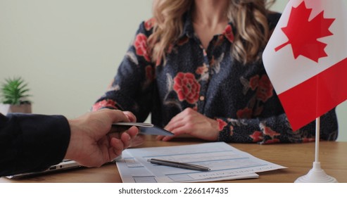 Canadian woman consular officer giving passport to male immigrant, work visa, citizenship. Visa Application online form immigration concept. Visa approval. - Shutterstock ID 2266147435