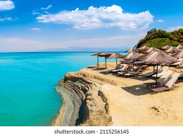 Canal D'Amour or Love Channel in Sidari, Corfu island in Greece. D'Amour beach with umbrellas and sun chairs on clay cliff over turquoise water of Mediterranean sea for relaxation and beautiful view.