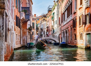 Canal in Venice, Italy with gondolier rowing gondola. Romantic Venetian waterway