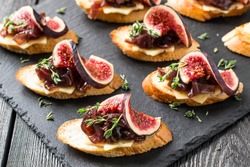 Canape Or Crostini With Toasted Baguette, Cheese, Onion Jam, Figs And Fresh Thyme On A Slate Board. Delicious Appetizer, Ideal As An Aperitif. Selective Focus