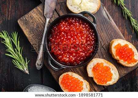 Canape toasts with red caviar, on old dark wooden table background, top view flat lay
