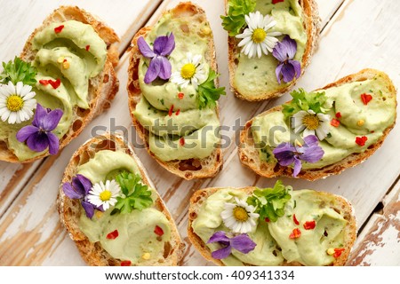Canapes with avocado paste and edible flowers
