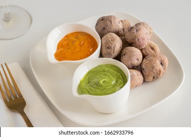 Canary Islands pdish Papas Arrugadas ( wrinkly potatoes) with Mojo picon (Red hot sauce) and  Mojo verde ( Green sauce)  on restaurant table   - Shutterstock ID 1662933796