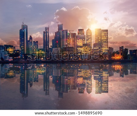 Canary Wharf business and banking area at sunset with beautiful reflection in the River Thames water. London, UK
