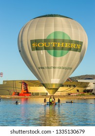CANBERRA, AUSTRALIA – March 11, 2019: A hot air balloon touches down on the lake in Canberra as Kayakers come to assist