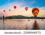 Canberra Ballon Spectacular, colourful hot air balloons float over iconic Telstra Tower and Lake Burley Griffin in early morning light.