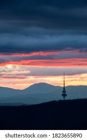Canberra Telstra Tower during sunset with layers of clouds and mountains in the background
