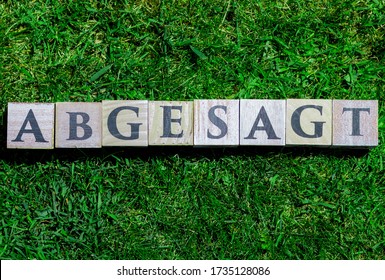 Canceled (German word: abgesagt) written on wooden blocks isolated on green grass background - Powered by Shutterstock