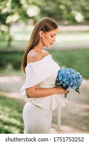 Cancelled Wedding. Sad Bride Looking At Bouquet Standing Alone In Park Outdoor. Vertical