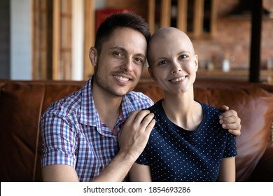 Cancer Is Not A Death Sentence. Portrait Of Smiling Loving Couple Posing On Couch Leaning Heads To Each Other Looking At Camera, Hopeful Husband Embracing Shoulders Of Wife Recovering From Oncology