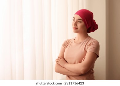 Cancer patient. Young woman with headscarf near window indoors, space for text - Powered by Shutterstock