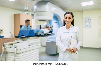 Cancer Treatment In A Modern Medical Private Clinic Or Hospital With A Linear Accelerator. Professional Doctors Team Working While The Woman Is Undergoing Radiation Therapy For Cancer