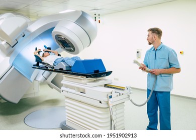 Cancer Treatment In A Modern Medical Private Clinic Or Hospital With A Linear Accelerator. Professional Doctors Team Working While The Woman Is Undergoing Radiation Therapy For Cancer