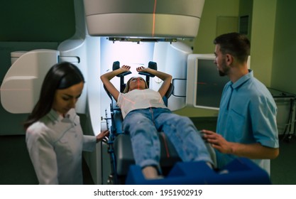 Cancer Treatment In A Modern Medical Private Clinic Or Hospital With A Linear Accelerator. Professional Doctors Team Working While The Woman Is Undergoing Radiation Therapy For Cancer