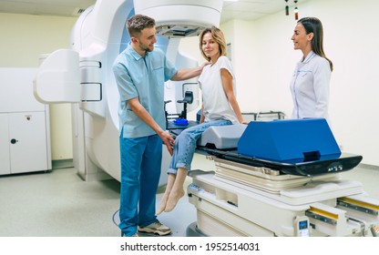 Cancer Treatment In A Modern Medical Private Clinic Or Hospital With A Linear Accelerator. Professional Doctors Team Working While The Woman Is Undergoing Radiation Therapy For Cancer