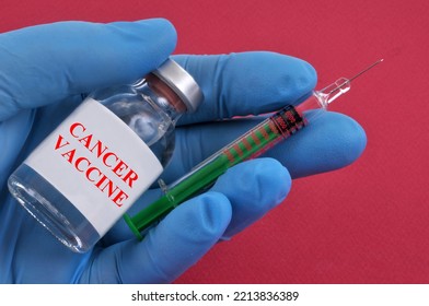 Cancer Vaccine Concept With A Syringe And Vial In A Gloved Hand Close Up On A Red Background