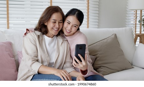 Candid attractive beautiful two people asia young lady girl use mobile phone take photo picture video overjoy sit at home sofa couch have good time day together quarantine in mum healthy health care. - Powered by Shutterstock