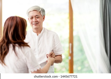 Candid Of Attractive Senior Asian Couple Dance Together At Home In Waltz Dance Exercise Activity Class For Older With Copy Space. Older Hold Hands Looking To Eyes With Love With Retirement Concept.