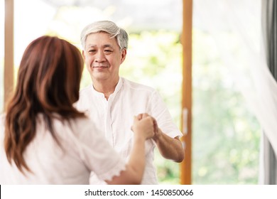 Candid Of Attractive Senior Asian Couple Dance Together At Home In Waltz Dance Exercise Activity Class For Older With Copy Space. Older Hold Hands Looking To Eyes With Love With Retirement Concept.