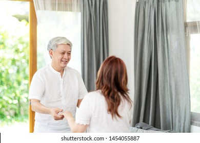 Candid Of Attractive Senior Asian Couple Dance Together At Home In Waltz Dance Exercise Activity Class For Older With Copy Space. Older Hold Hands Looking To Eyes With Love With Retirement Concept.