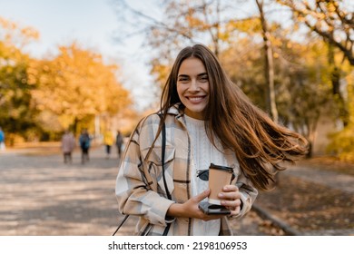 candid attractive young smiling woman walking in autumn park with coffee wearing checkered coat, happy mood, fashion style trend, long brown hair - Shutterstock ID 2198106953