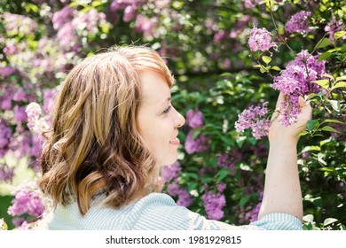 Candid Authentic Portrait Of 30s 40s Caucasian Blonde Woman With Lilac Flowers. 30 40 Year Old Woman Enjoying Life In Lilac Flowers Nature Background. Reinvention, Life Changes, Reinvent Yourself