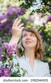 Candid Authentic Portrait Of 30s 40s Caucasian Blonde Woman With Lilac Flowers. 30 40 Year Old Woman Enjoying Life In Lilac Flowers Nature Background. Reinvention, Life Changes, Reinvent Yourself