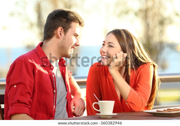 Candid couple date\
falling in love flirting in a terrace looking each other with\
tenderness thinking to\
kiss