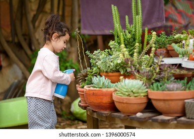 Candid cozy image cute child, little gardener sprinkling plants. Young sweet girl sprays succulent and cactus on summer courtyard garden. - Powered by Shutterstock