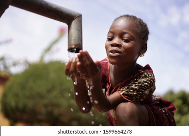 Candid Image Of African Schoolgirl Drinking Safe Water From Tap Outdoors In Bamako, Mali