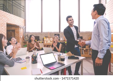 Candid Of Indian Creative Design Man Smiling And Shaking Hands With Coworker Man Or Colleague And Other Clapping Hand At Office Workplace. Introduction To Team Or Marketing Group Concept Soft Tone.