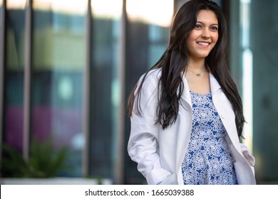 Candid Lifestyle Portrait Of A Female Medical Professional In A White Coat Walking Outside Workplace