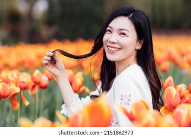 Candid Lifestyle Portrait Of Happy Young Beautiful Asian Sexy Woman Enjoying Life Outdoor In Park At Spring. Smiling Millennial Girl With Perfect Clear Glow Skin And Long Brunette Hair