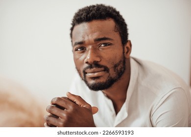 Candid millennial authentic diverse portrait of african american man relax time at apartment in neutrals tones interior.Domestic life multi ethnic male having thoughtful facial expression in day light - Powered by Shutterstock