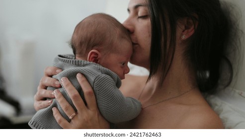 Candid mother holding newborn baby in bed showing love care and affection - Powered by Shutterstock