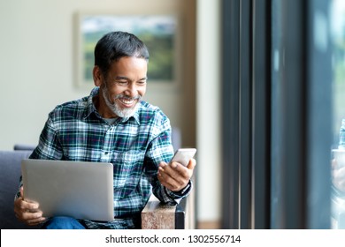 Candid of old asian retired man using mobile phone to transfer money online or financial payment and read text, smile or laugh with happy and positive. Senior asian with digital technology concept.