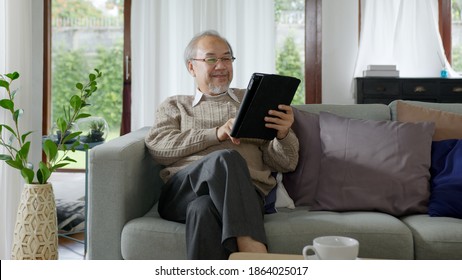 Candid Of Old Asian Retired Man Using Tablet Computer To Transfer Money Online Or Financial Payment And Read Text, Smile Or Laugh With Happy And Positive. Senior Asian With Digital Technology Concept