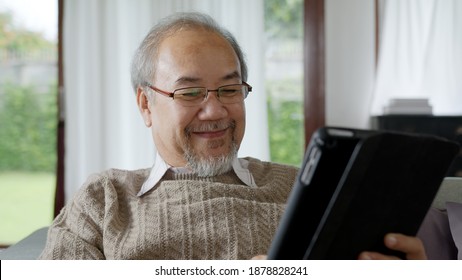 Candid Of Old Asian Retired Man Using Tablet Computer To Transfer Money Online Or Financial Payment And Read Text, Smile Or Laugh With Happy And Positive. Senior Asian With Digital Technology Concept