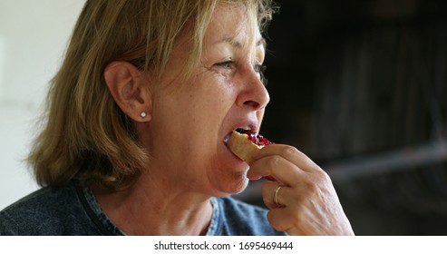 Candid Older Woman Eating Toast With Jelly Morning Breakfast.