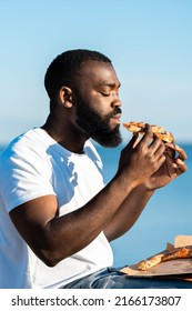 Candid Portrait Of African American Young Black Man Eating Pizza.