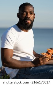 Candid Portrait Of African American Young Black Man Eating Pizza.