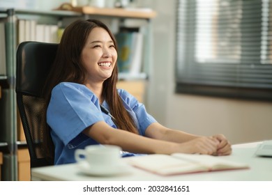 Candid portrait of Asian female doctor or nurse with stethoscope smiling while sitting in the room. Optimistic medical people on duty. Portrait of medic happiness.