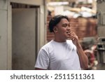 Candid portrait of a LBGT person biting his finger. A young Filipino residing in an squatter area. Shantytown background.