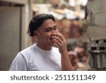 Candid portrait of a LBGT person giggling. A young Filipino residing in an squatter area. Shantytown background.