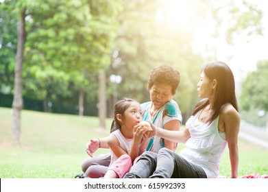 Candid Portrait Of Multi Generation Asian Family At Nature Park. Grandmother, Mother And Daughter Outdoor Fun. Morning Sun Flare Background.