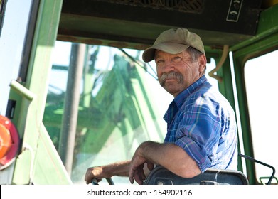 A Candid Portrait Of A Senior Male Farmer Sitting In A Tractor.