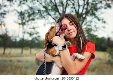 Candid Portrait Young Adult Woman With Tenderness Embracing Purebred Beagle In Rural Settings. Female Owner And Pet. Authentic Lifestyle. Backyard. Outdoor Space. Selective Focus On Dog