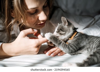 Candid portrait of Young woman is resting with kitten on the bed at home one sunny day. Girl play with outbred kitten. - Shutterstock ID 2194394565